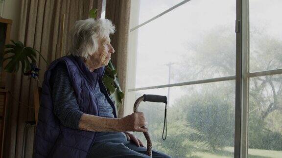 一个快乐的舒适的老年白人妇女在夏天看窗外的广角拍摄
