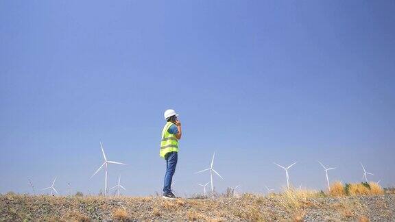 男性工程师使用智能手机在风力涡轮机农场工作
