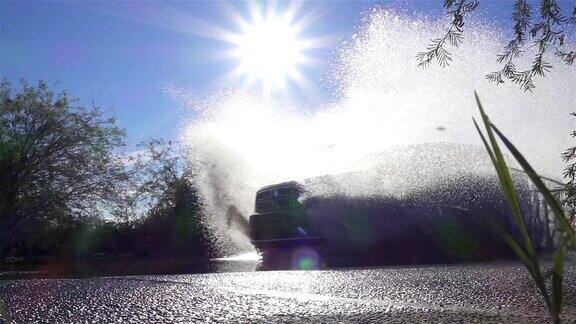 慢镜头:一辆SUV从大水坑上冲过把水溅到摄像机上
