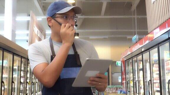 一位亚洲杂货店经理使用电子平板电脑工作