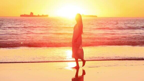一位亚洲妇女喜欢在日落时在海滩上散步缓慢的运动