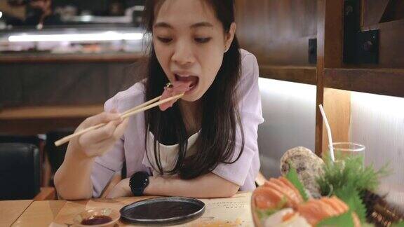 Z一代年轻的亚洲女性享受着豪华的日本料理与什锦寿司海鲜牡蛎生鱼片在餐厅的餐桌上新鲜供应亚洲美食和食物外出就餐的生活方式