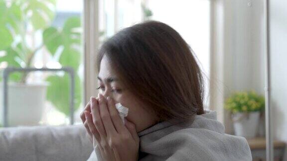 患有流感的亚洲妇女坐在家里客厅的沙发上