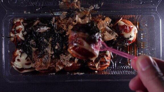 章鱼烧摆放在一个塑料食品容器内吃前由手拿电梯展示