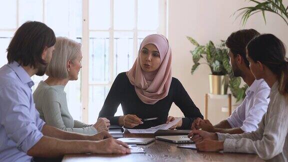 亚洲穆斯林女性公司领导在团队会议上讨论文书工作