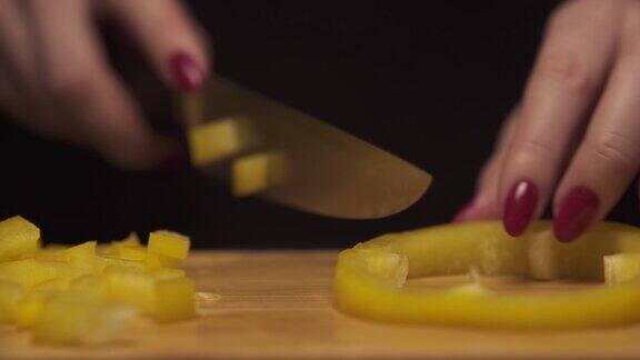 现代厨房里女人用手在木板上切黄椒