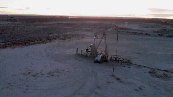 视差日落无人机拍摄的水力压裂油和天然气泵千斤顶在西德克萨斯油田黄昏工作