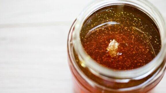 蜂蜜从玻璃罐里的蜂蜜勺中滴落