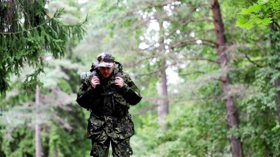年轻的士兵护林员或猎人背着背包在森林里行走