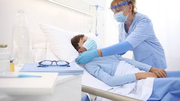 护士在病床上照顾患儿佩戴防护口罩树立冠状病毒防护理念