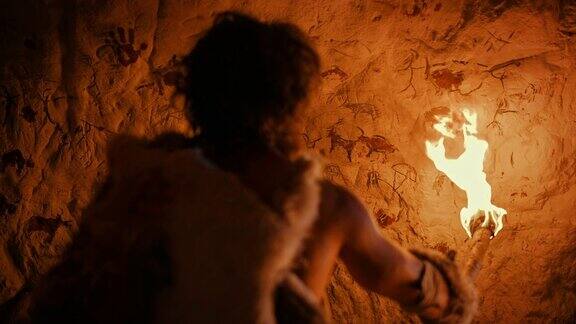 穿着兽皮的原始穴居人晚上站在洞穴里拿着火把看墙上的画岩画洞穴艺术岩画后视图