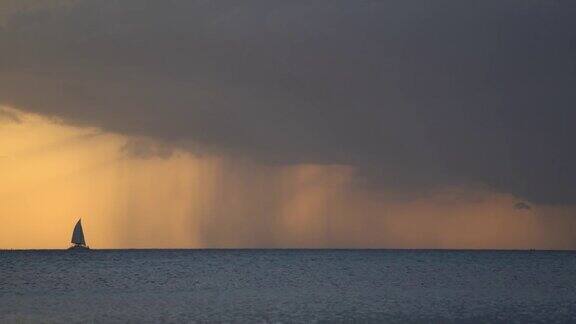 在引人注目的日落时分一艘帆船带着雨进入暴风雨中激情与梦想