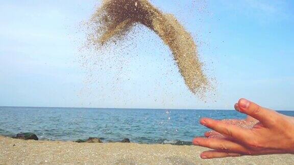 一个人在天空和大海的背景上撒沙子缓慢的运动