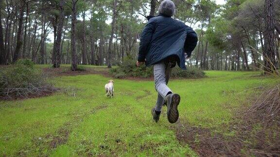 一个十几岁的男孩和他的金毛猎犬在树林里玩耍奔跑