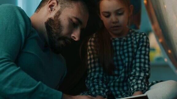 父亲和女儿在家里的帐篷里看书
