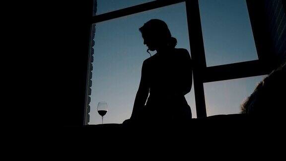 日落时分房间里一个女孩坐在酒杯旁的剪影