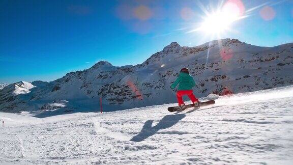 SLOMOTS女性滑雪板在阳光下骑下白雪覆盖的山坡