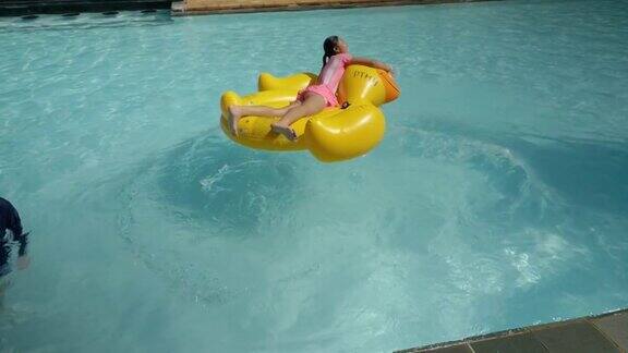 快乐的亚洲女孩跳黄鸭橡皮筏在游泳池期间与家人度假生活理念