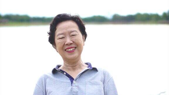 快乐的亚洲资深妇女在湖愉快地微笑