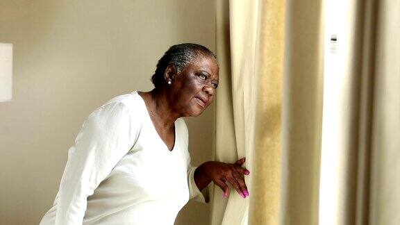 严肃的资深非裔美国妇女望着窗外