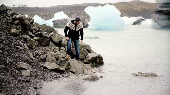 年轻英俊的男子站在Jokulsalon冰礁湖的岸边看着冰岛的冰川