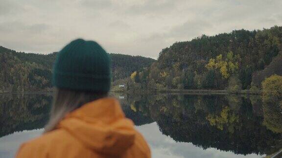 在挪威湖边徒步旅行的女人:秋叶