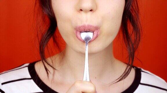 涂着口红的女人用勺子吃酸奶