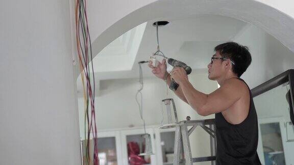 亚洲华人成熟男子电工覆盖电缆安装一盏灯在家庭装修