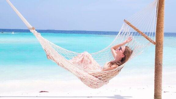 美丽的女人躺在热带海滩的吊床上