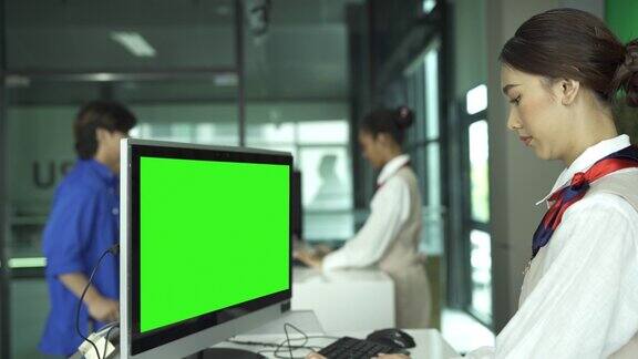 女性地勤人员在航空公司值机柜台使用绿色屏幕显示器工作