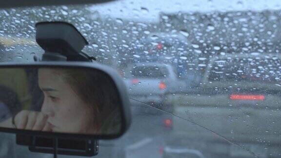 女人在雨中开车女人的脸映照在汽车后视镜上