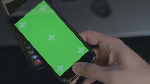 俯视图的人使用智能手机非接触式支付手机上的绿色屏幕模板