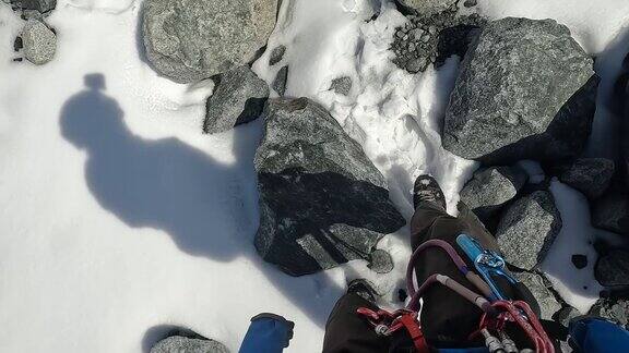 一名装备齐全的登山者沿着雪道走过岩石腿部视图