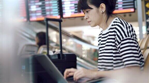亚洲年轻女子在等待航班时使用笔记本电脑
