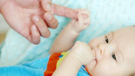 婴儿握着父亲的手指咬他的拳头理念:父母的支持与关怀