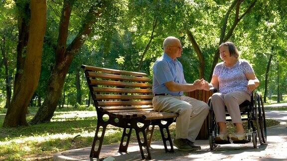 老男人和坐轮椅的女人在公园外面