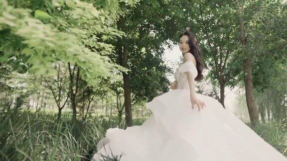年轻的亚洲女孩穿着白色的长尾婚纱对着镜头微笑幸福的新娘