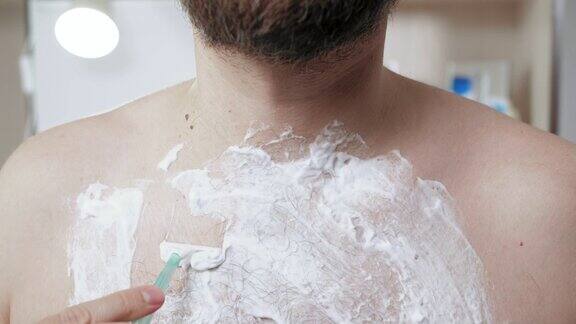 男人刮胸毛一名蓄着胡须的中年白人男子开着一次性剃须机在胸前刮泡沫特写镜头