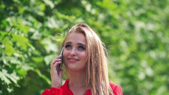 热情的女孩在夏天自拍美丽的年轻女子与长头发在红色衬衫拍照自己在绿色的树的背景