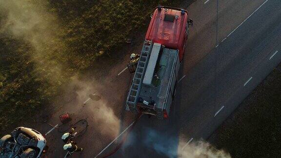 鸟瞰图:救援队的消防队员和护理人员在车祸交通事故现场工作准备设备急救和帮助从燃烧的车辆中救出受伤和被困人员