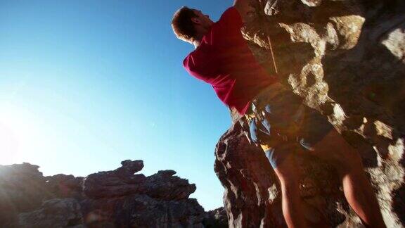 专注于攀岩者抓住抓地力悬挂在巨石上