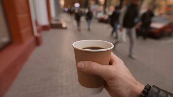 第一人称男人拿着咖啡杯走在城市的街道上
