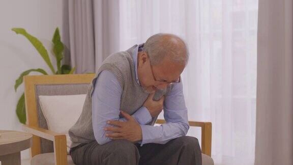 亚洲老人坐在客厅的沙发上因心脏病胸口疼痛
