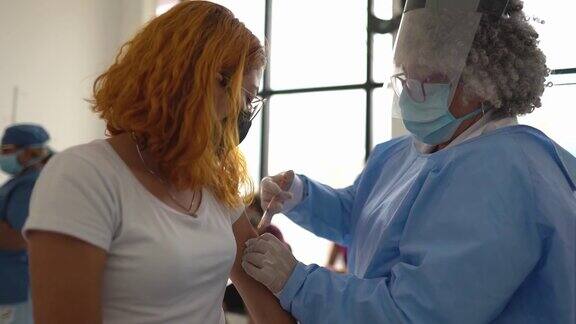 年轻妇女正在接种疫苗-戴口罩