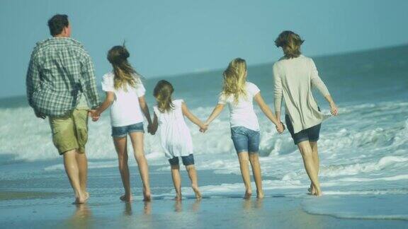 快乐的白人父母年轻的女儿在户外海滩散步