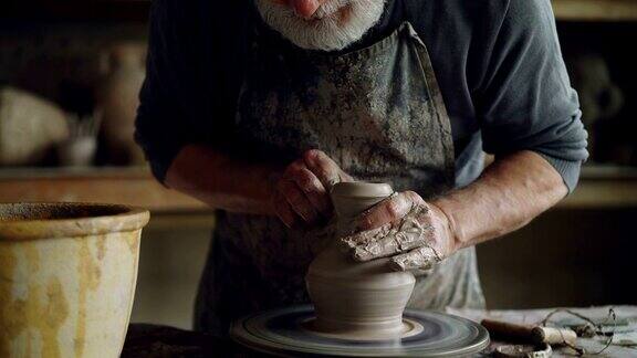 勤奋的高年级陶工正在用清水把双手打湿并在旋转的掷轮上触摸陶罐大胡子男子正专注于工作