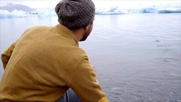 年轻男子在冰岛的冰川泻湖上撇石头