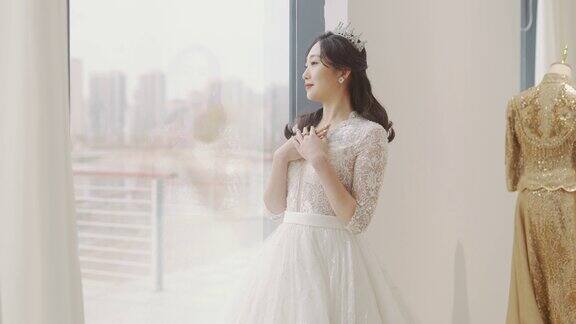 一位身着婚纱的年轻女子站在落地窗前