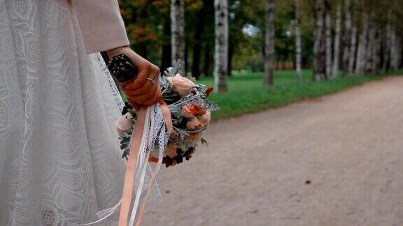 新娘手捧一束美丽的鲜花在公园里散步