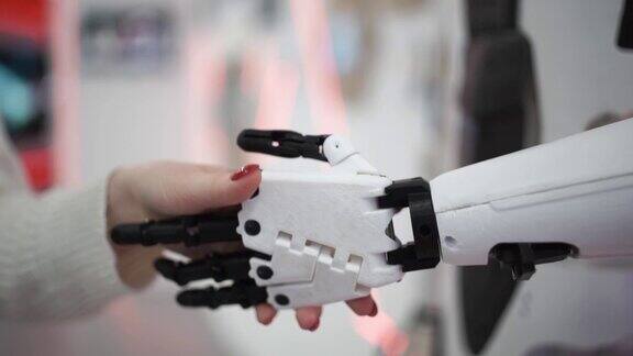 一个小女孩的手和一个机器人握手人类与人工智能互动